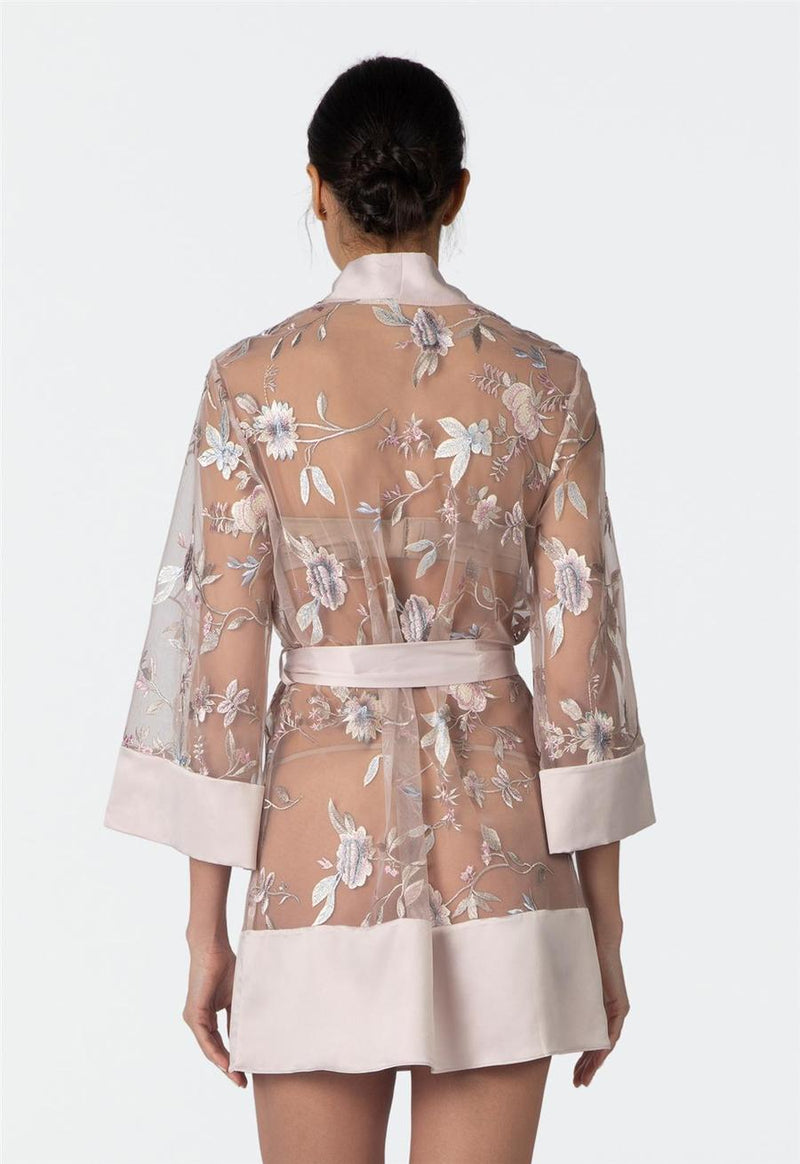Woman wearing a floral sheer sepia rose colored robe with a white background