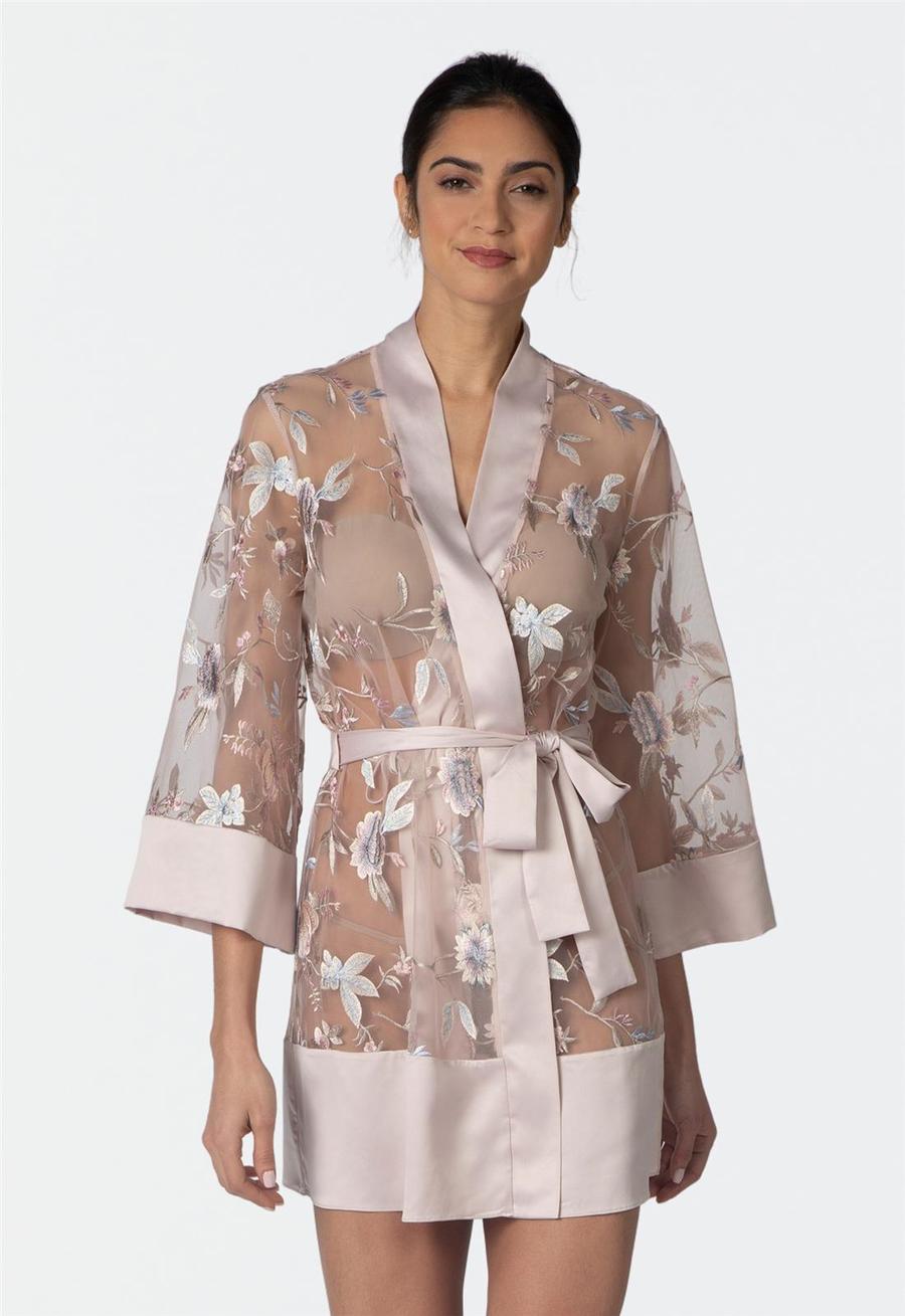 Woman wearing a floral sheer sepia rose colored robe with a white background
