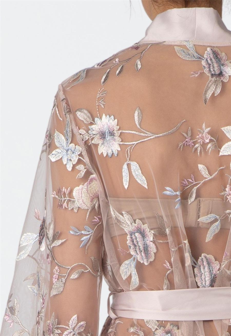 Woman wearing a floral sheer sepia rose colored robe with a white background