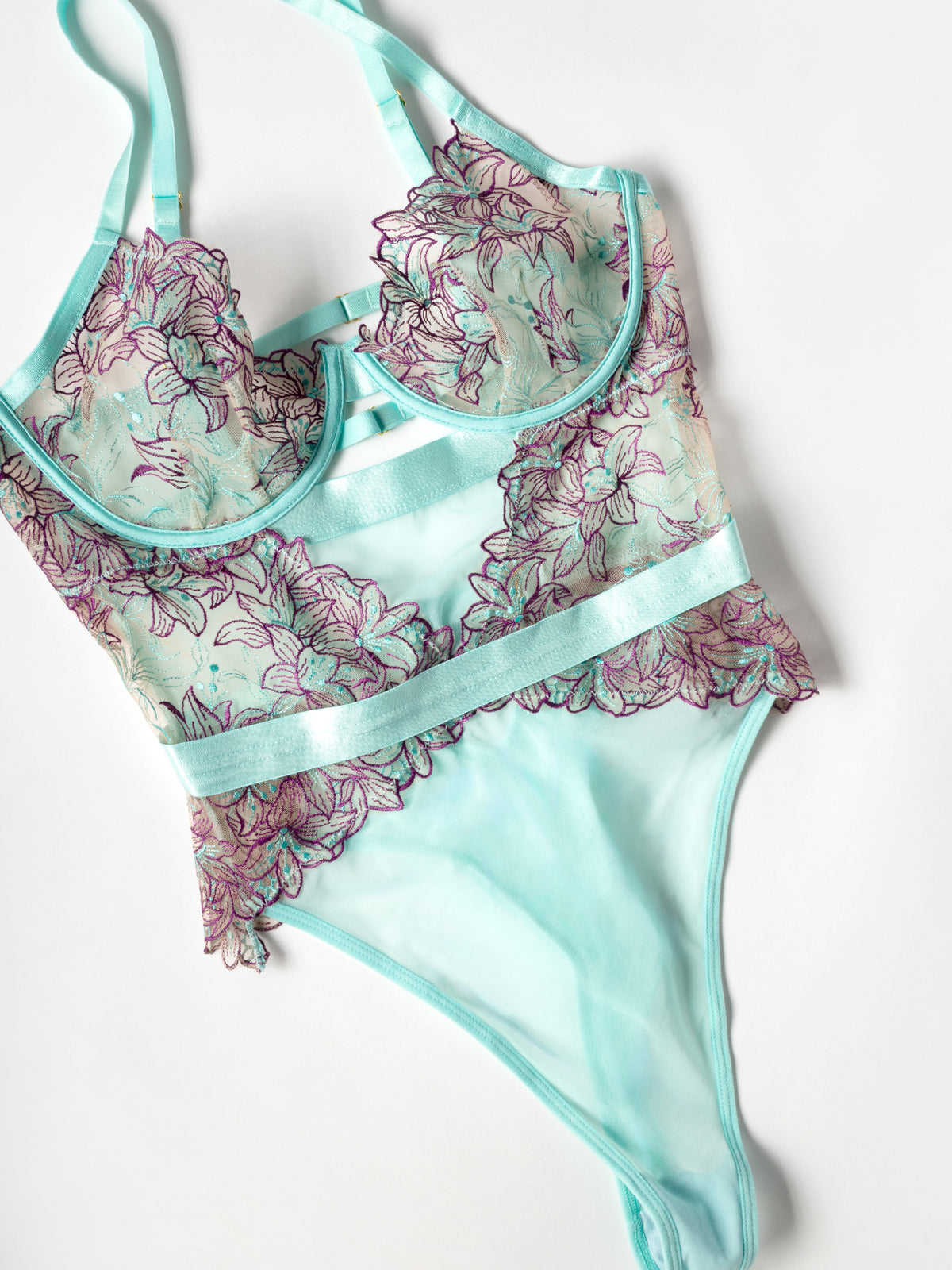 Teal lingerie set with floral patterns on a white background