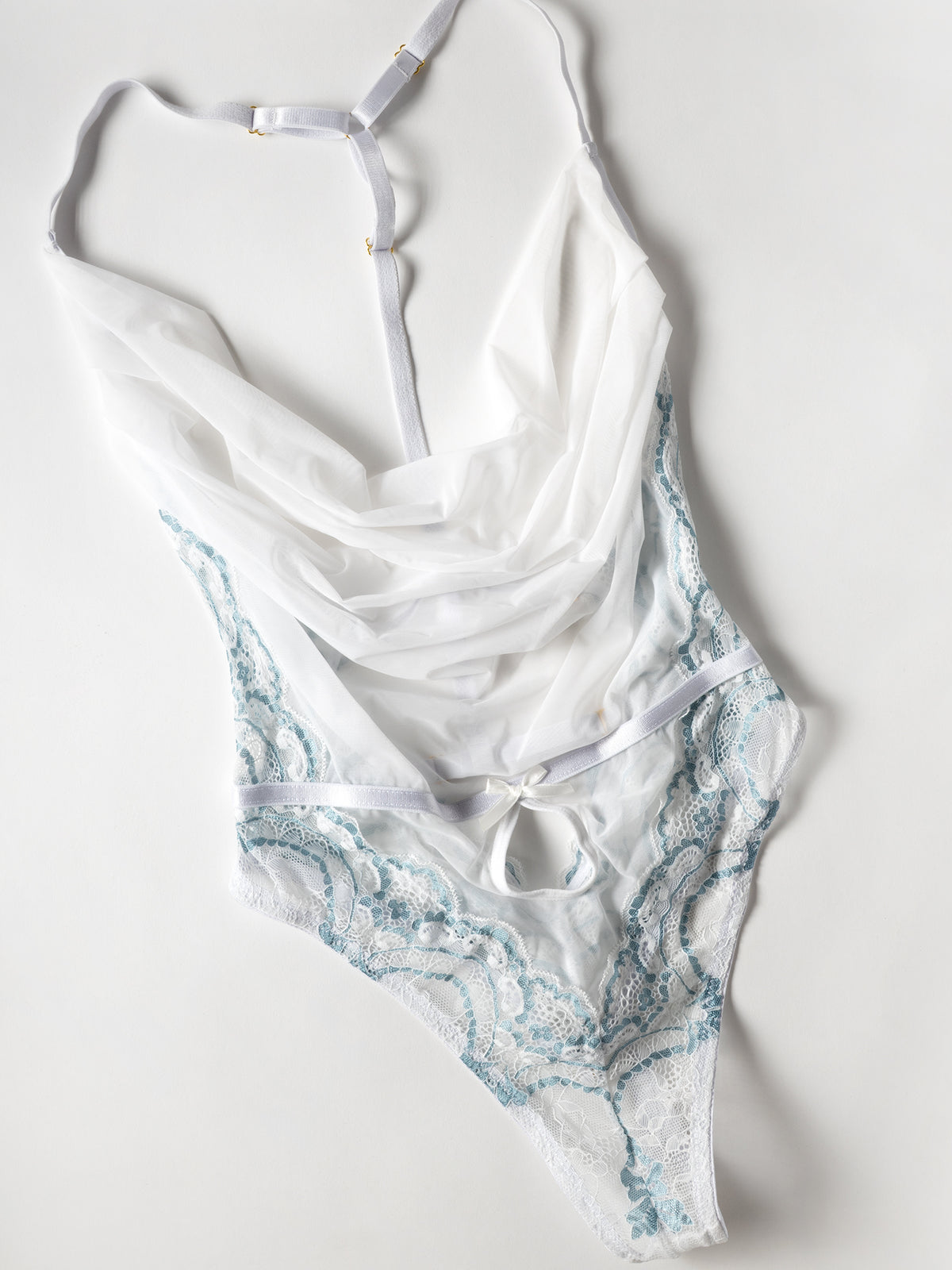 flat lay of a Woman wearing a Victoria sheer halter teddy in white and milky blue with cowl neckline, lace mesh, and G-string back