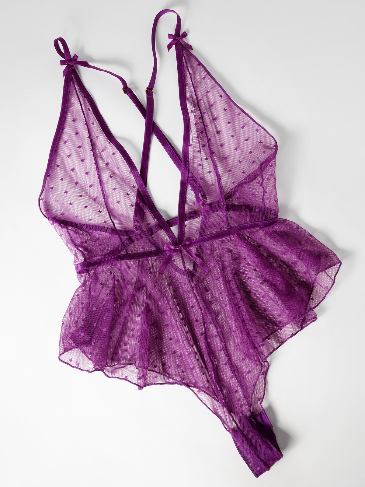 Flat lay of a  Tinsley sheer mesh romper with dotted pattern, plunge neckline, and adjustable straps.