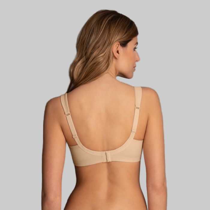 Woman wearing a beige bra against a gray background