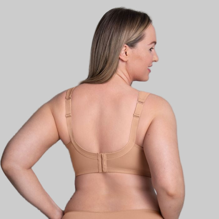 Woman wearing a beige bra against a gray background