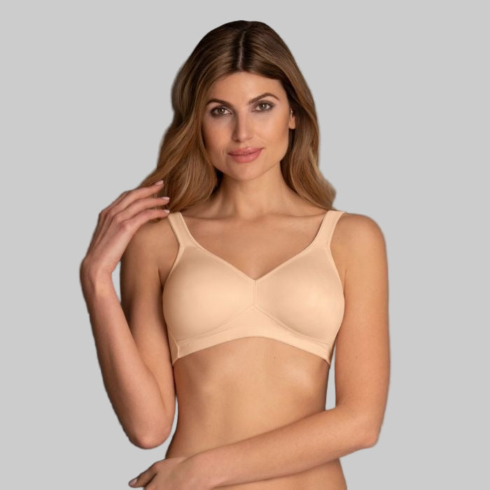 Woman wearing a beige bra against a gray background