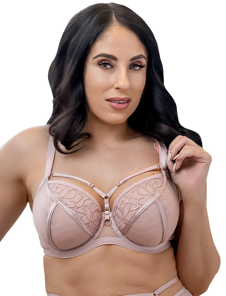 Woman wearing a light rose colored bra with floral lace details on a white background