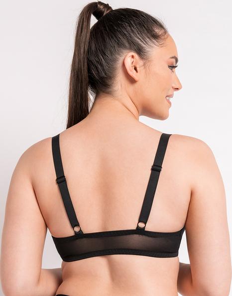 Woman wearing a black bralette on a plain background