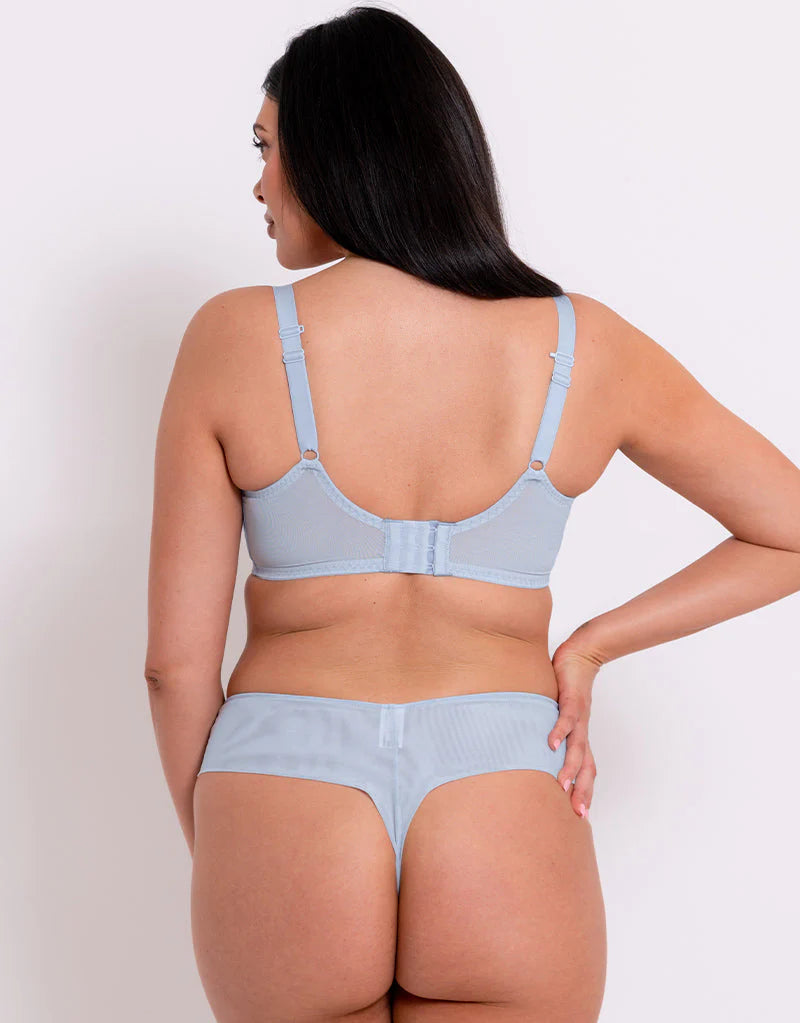 Woman wearing a light blue bra and underwear set against a white background