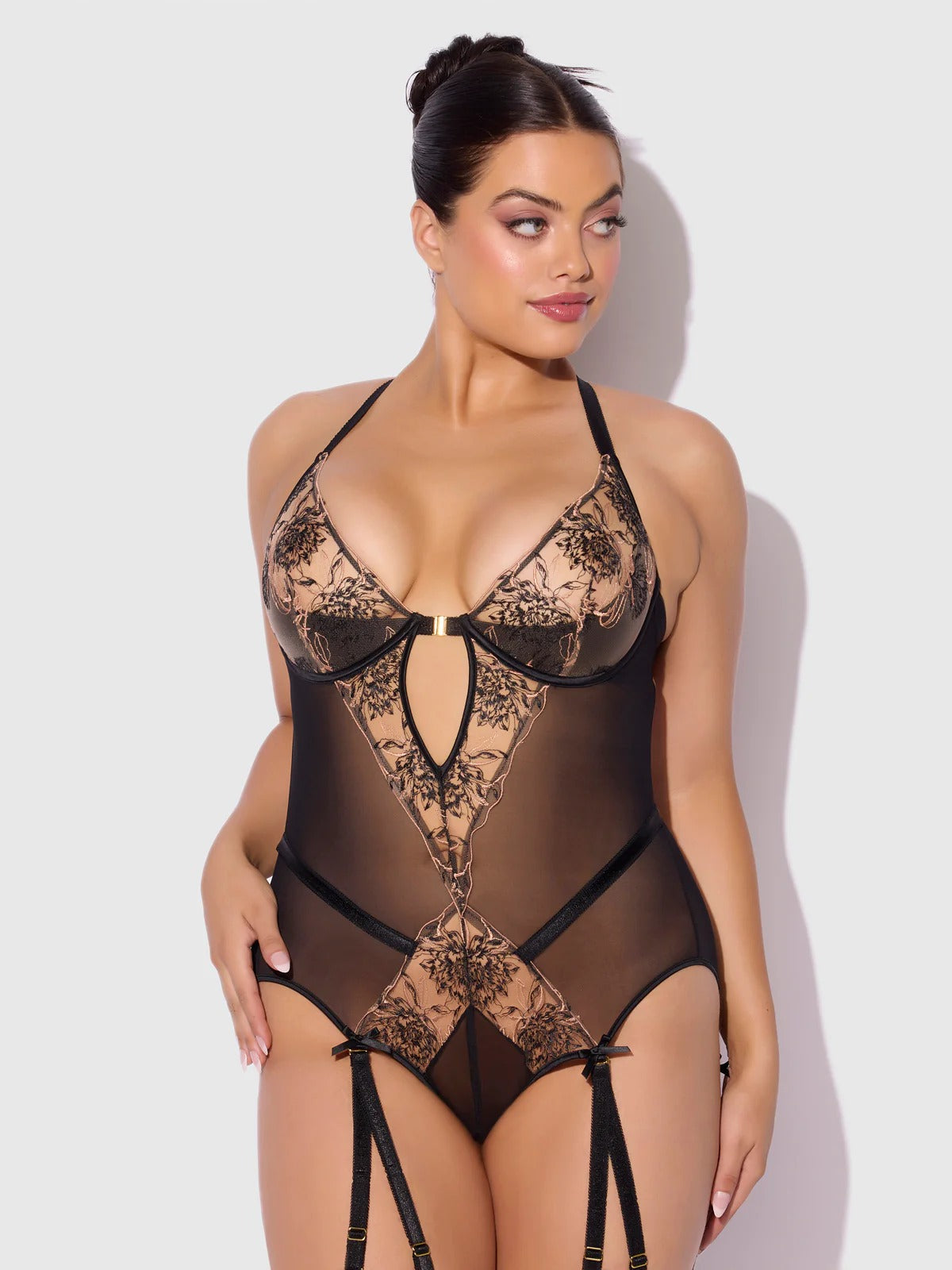 Woman wearing a black lace lingerie set against a white background