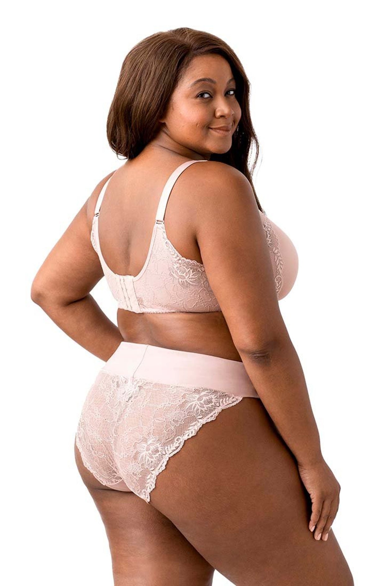 Woman wearing a light pink lingerie set with lace details on a white background