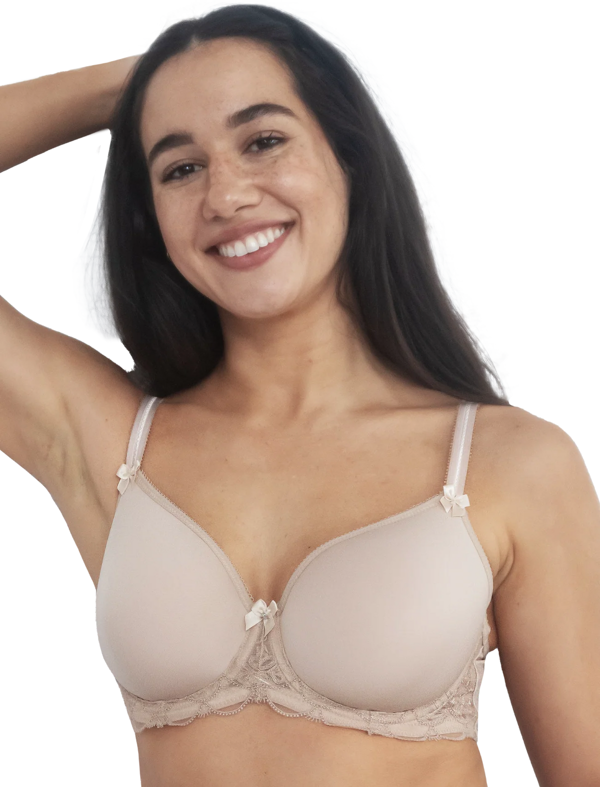 A smiling woman with long dark hair wearing a light beige underwire bra with lace trim and small bow details on the straps, photographed against a plain white background.