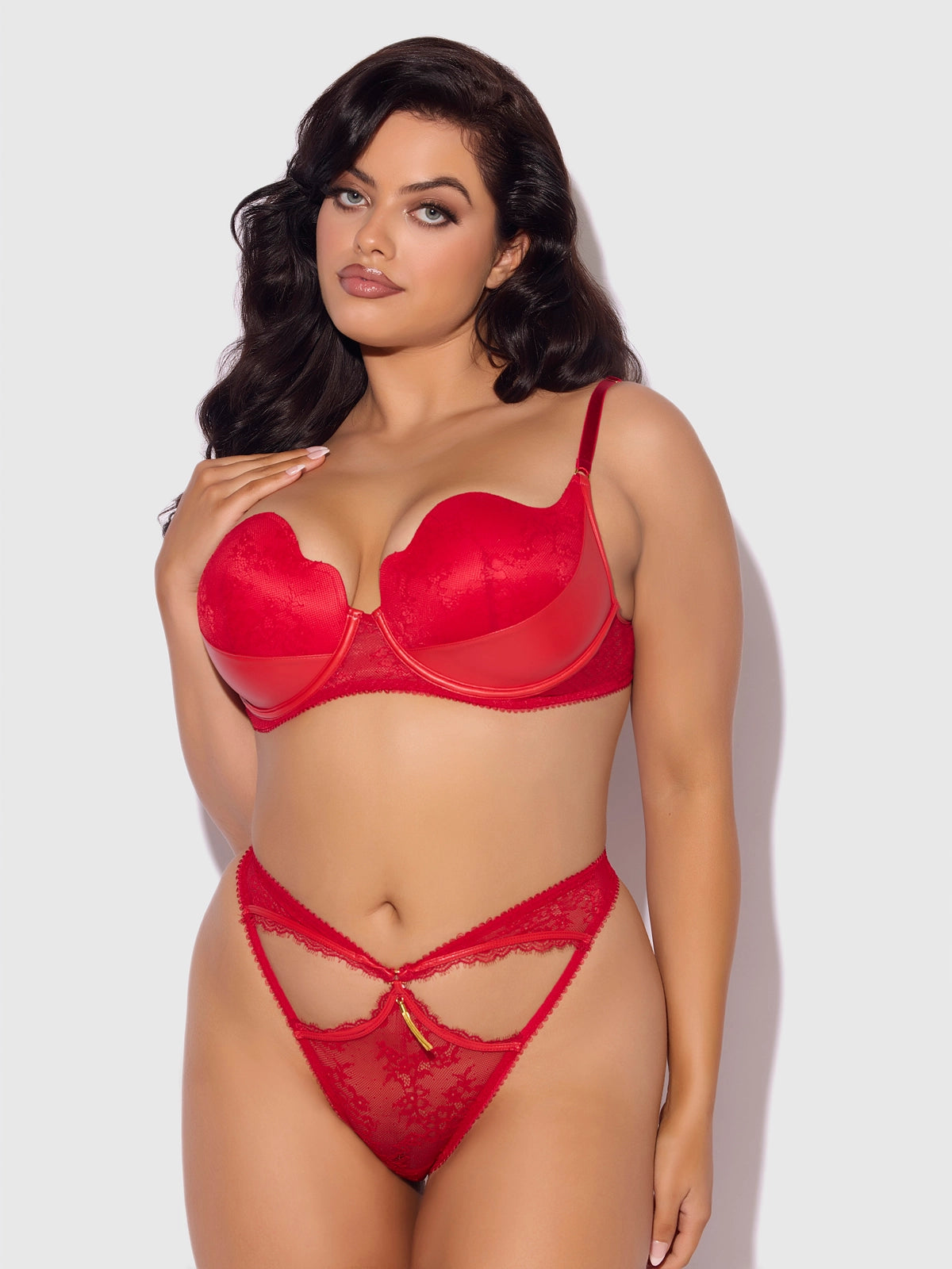 plus size woman wearing a Kiki lace and faux leather balconette bra and open-back hipster panty lingerie set with cutout and tassel details.