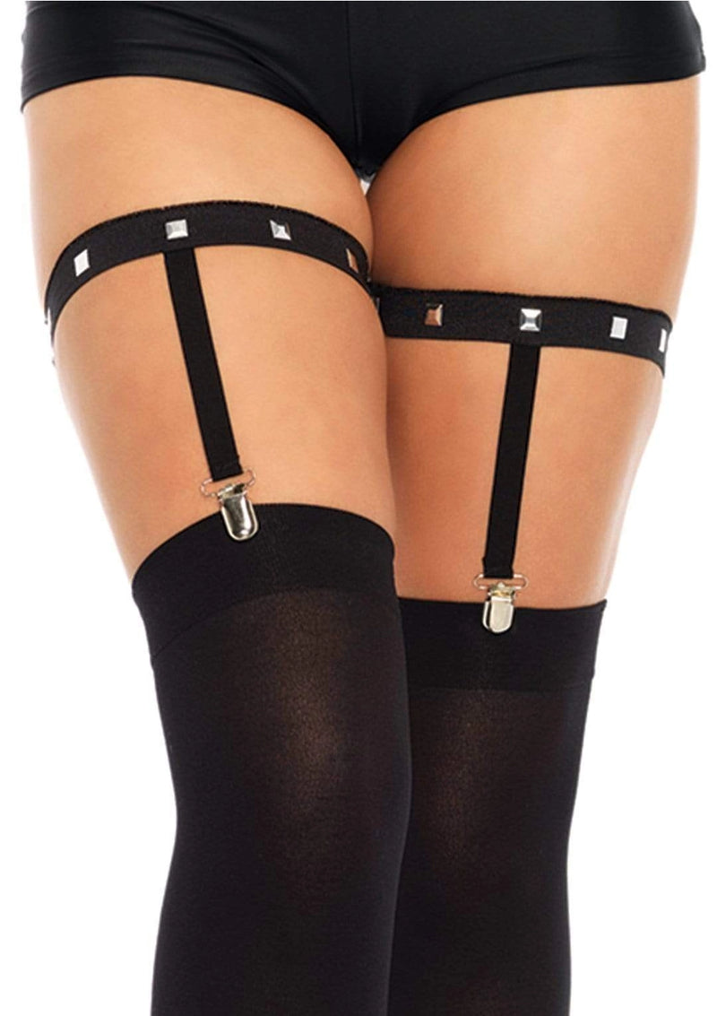 Black garter straps with gold clasp worn with black stockings on a white background