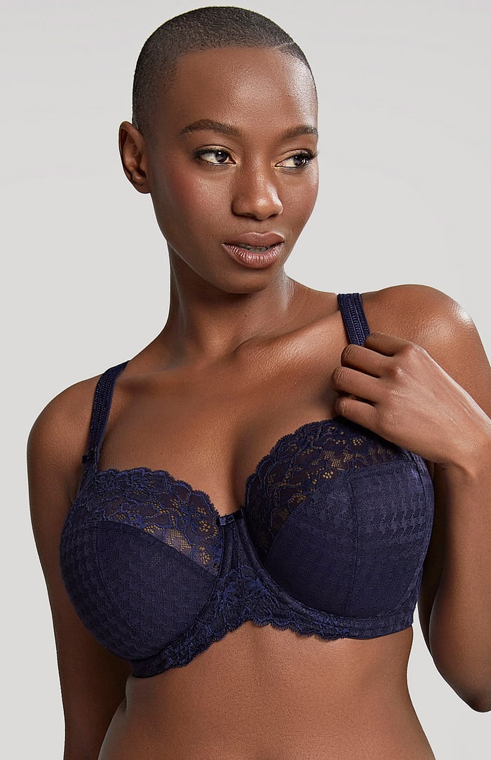 Woman wearing a navy blue lace bra against a plain background