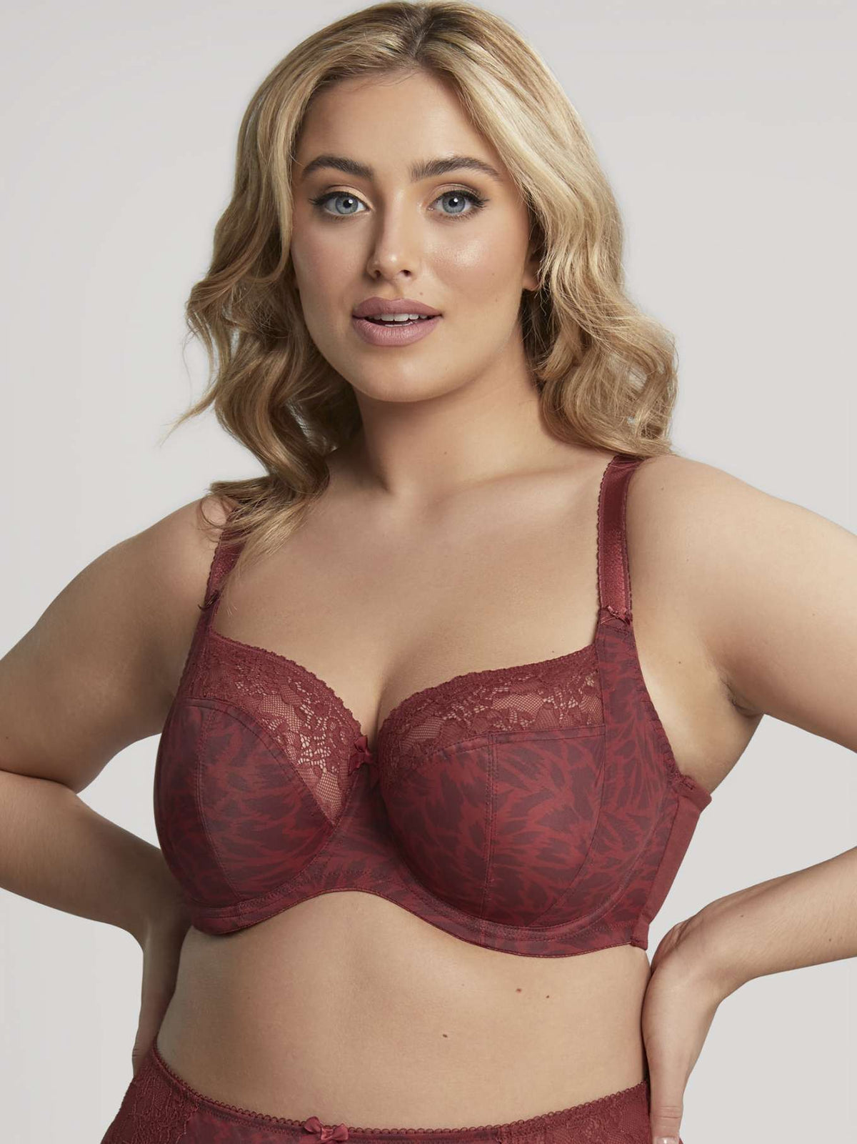 Woman wearing a red lace bralette against a plain background