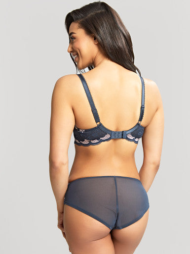 Woman wearing a navy blue bra and panties set on a gray background