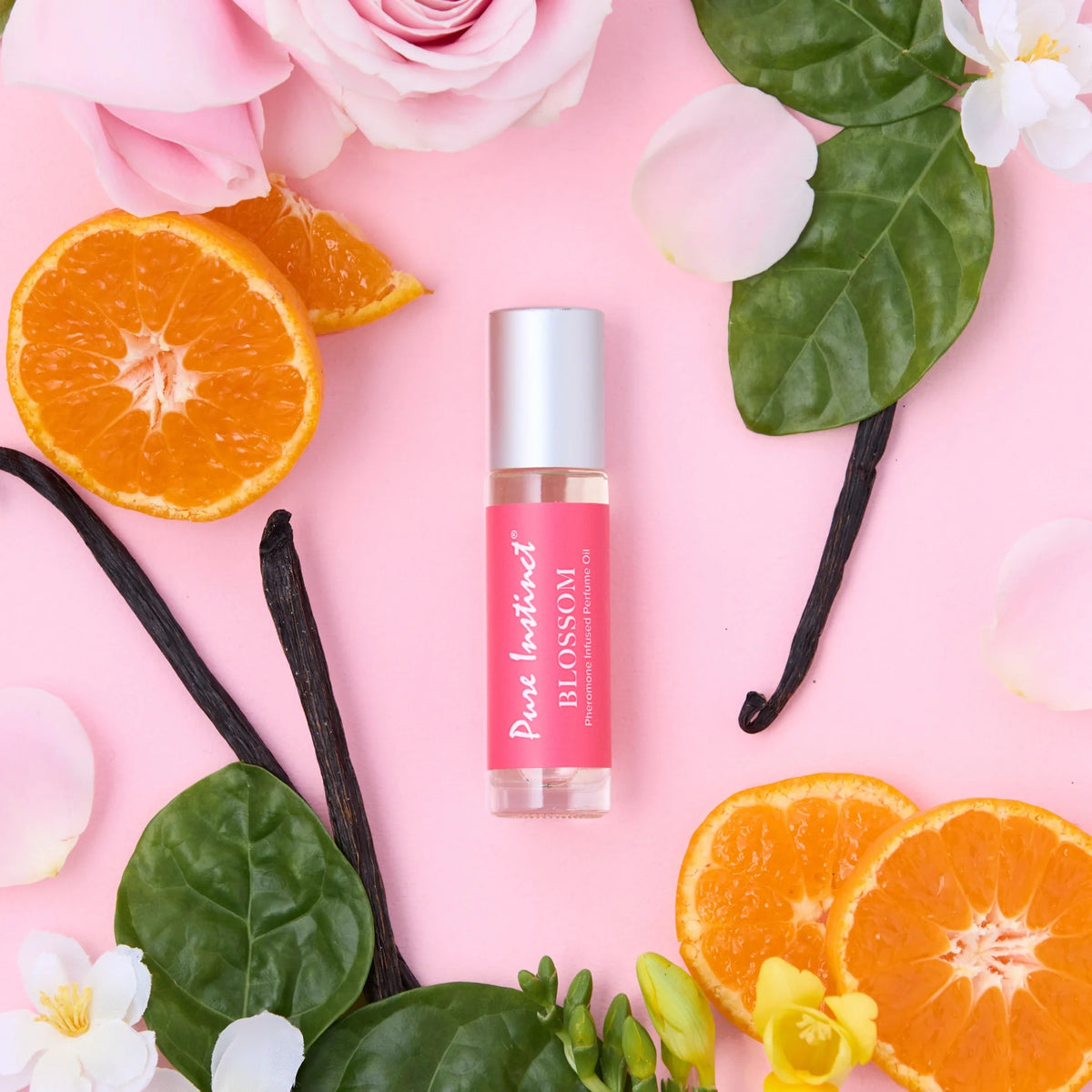 Roll-on bottle with pink label on a pink background with oranges, roses, and vanilla beans.