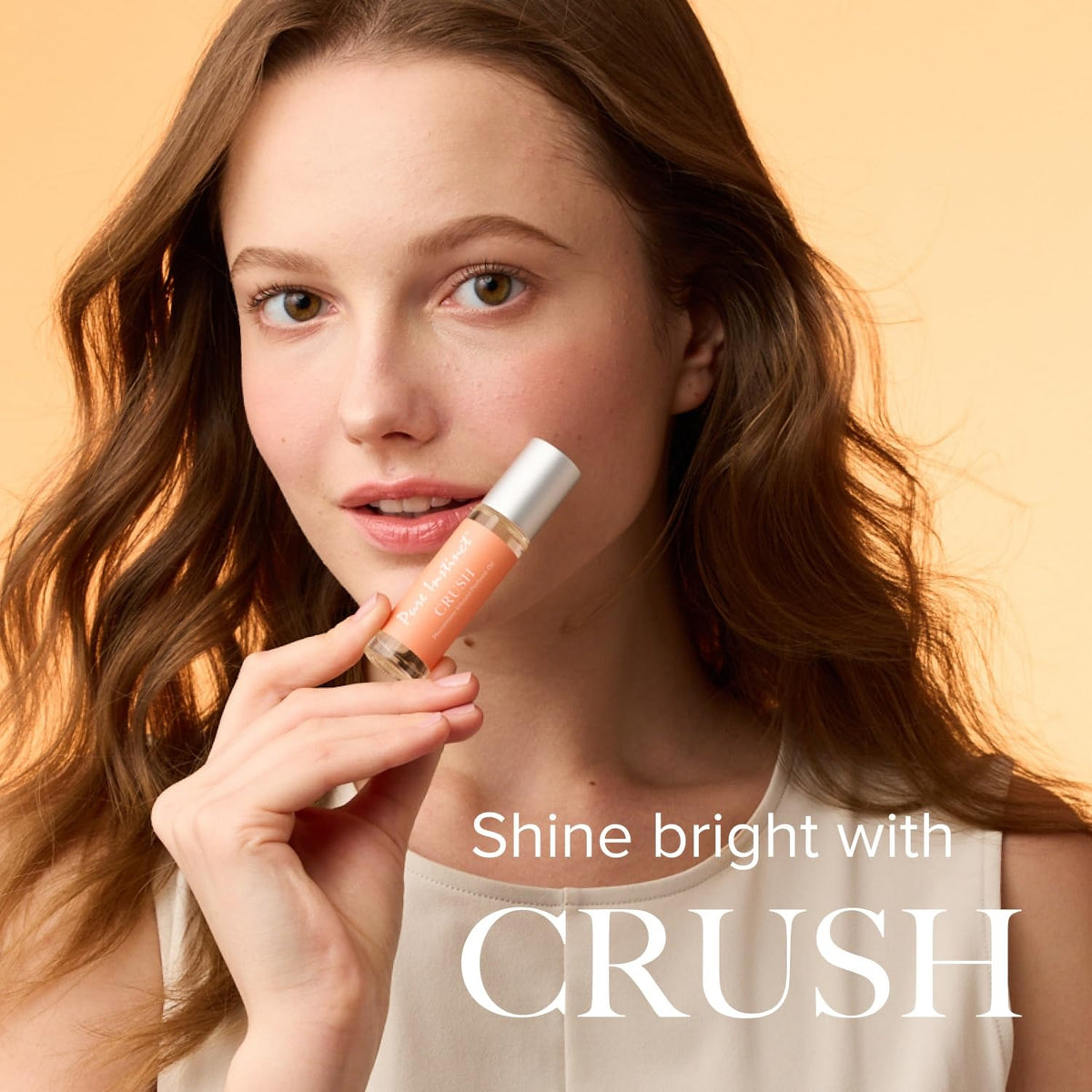 Woman holding a lip gloss with 'Shine bright with CRUSH' text on a beige background