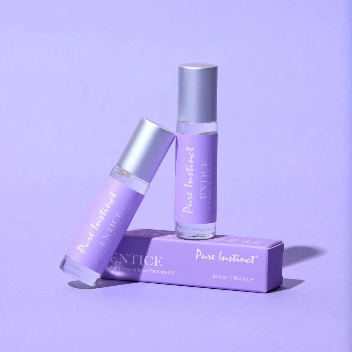 Two bottles of 'Pure Instinct' perfume on a purple background