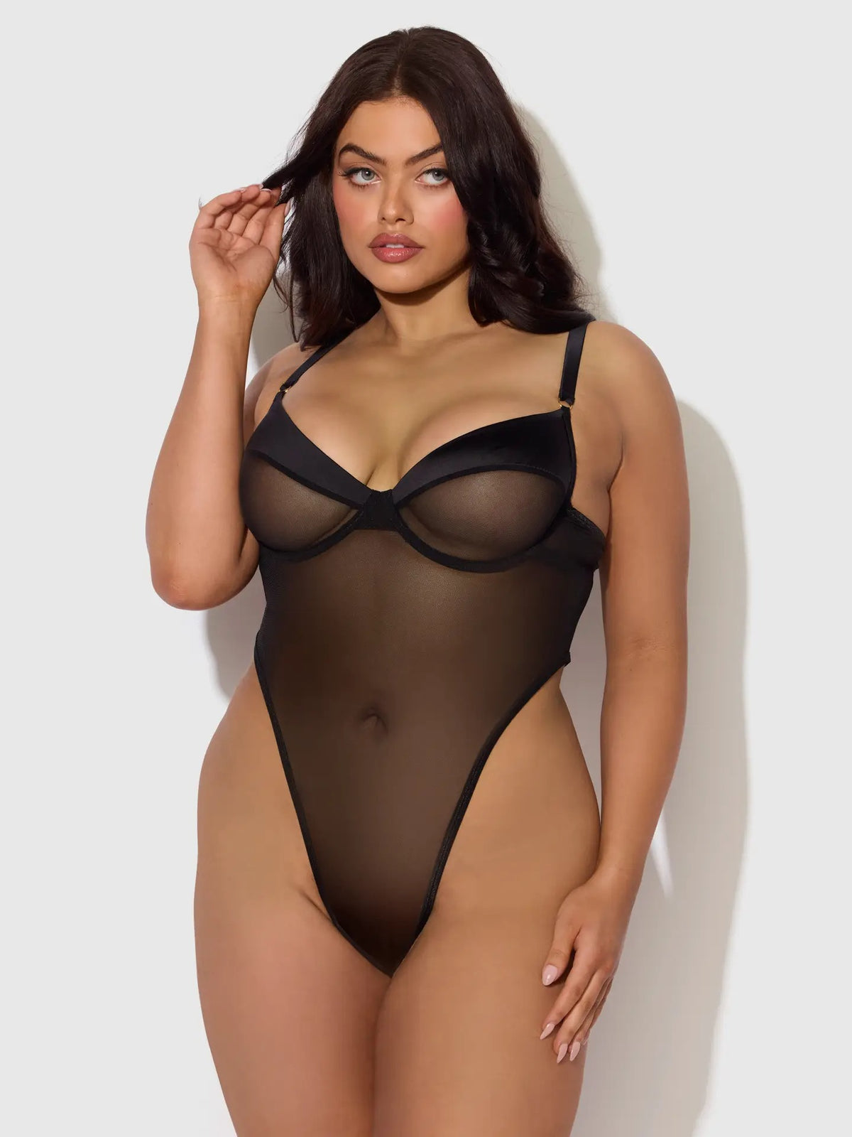 Plus sized woman wearing a Raquel Mesh & Silky Micro Bodysuit featuring sheer underwire cups and a body-contouring silhouette.