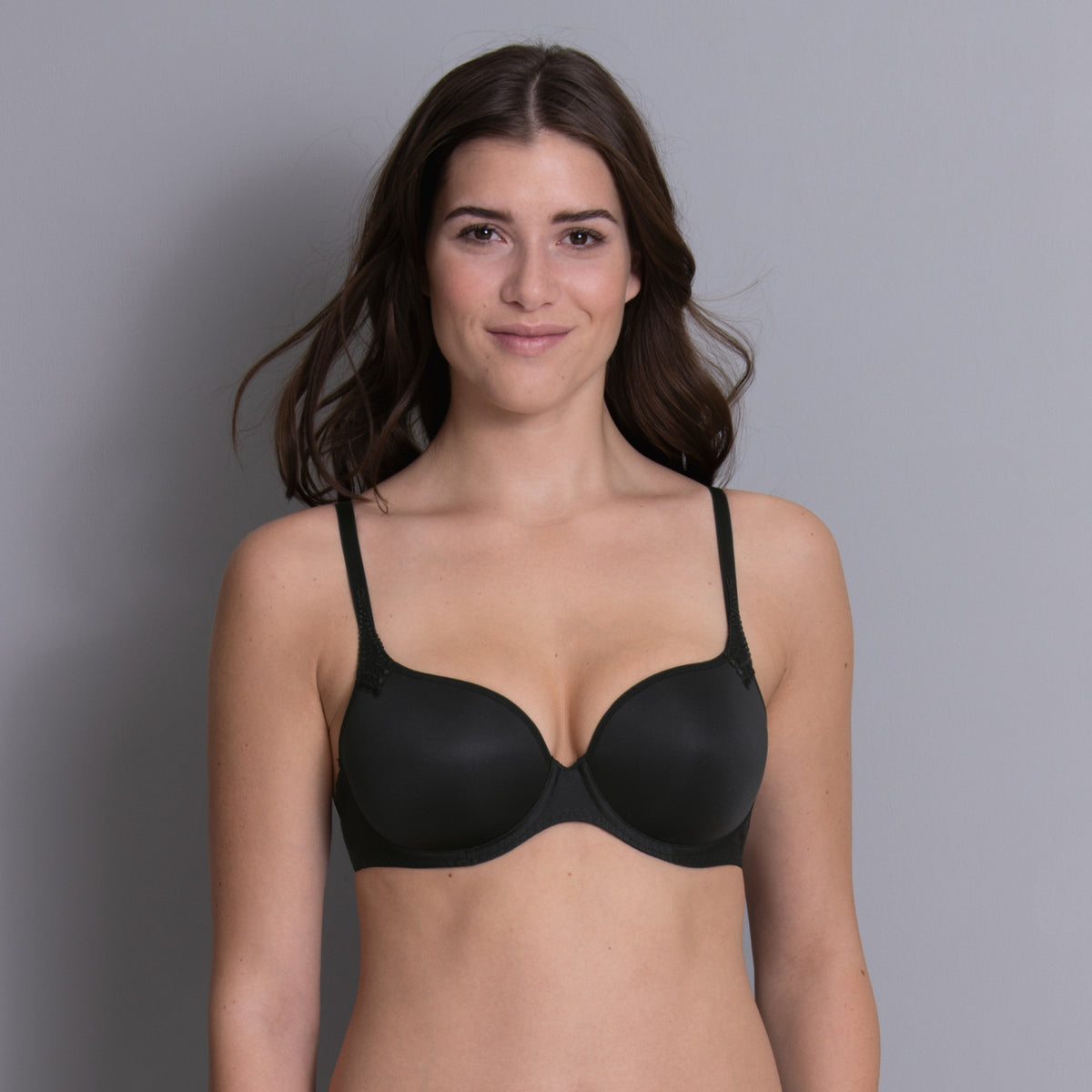 Woman wearing a black bra against a gray background