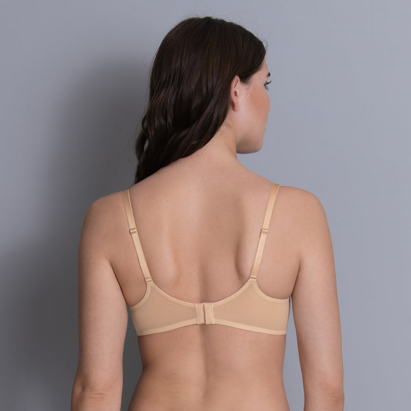 Woman wearing a beige bra against a gray background