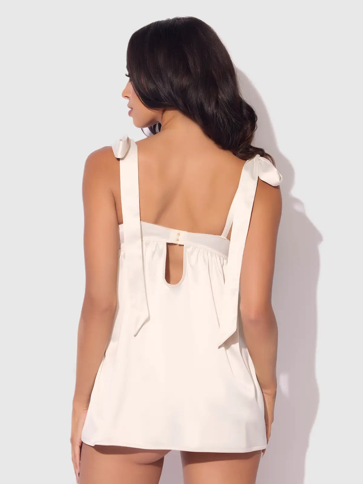 Woman wearing a white dress with cut-out back design on a light gray background