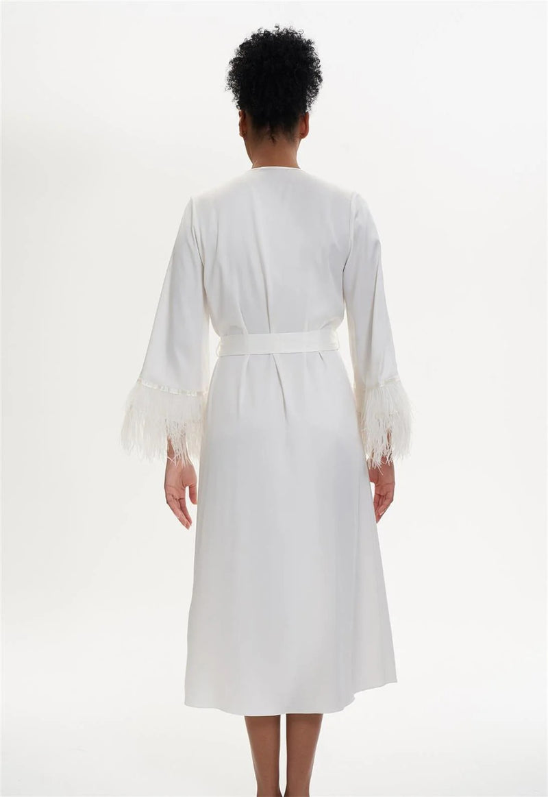 Person wearing a white dress with long sleeves on a white background