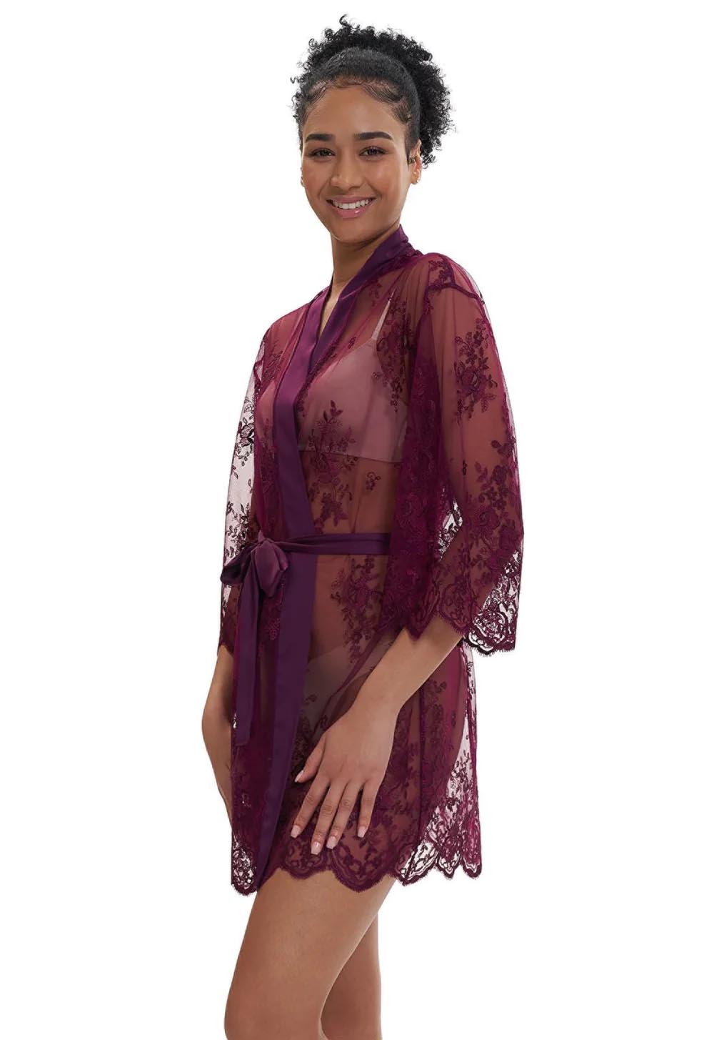 Woman wearing a sheer burgundy lace robe on a white background
