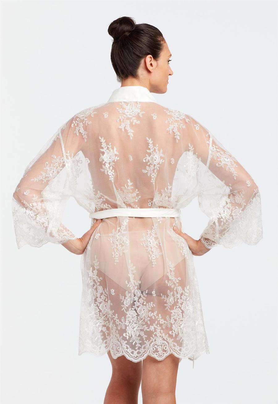 Woman wearing a sheer white lace robe on a light gray background