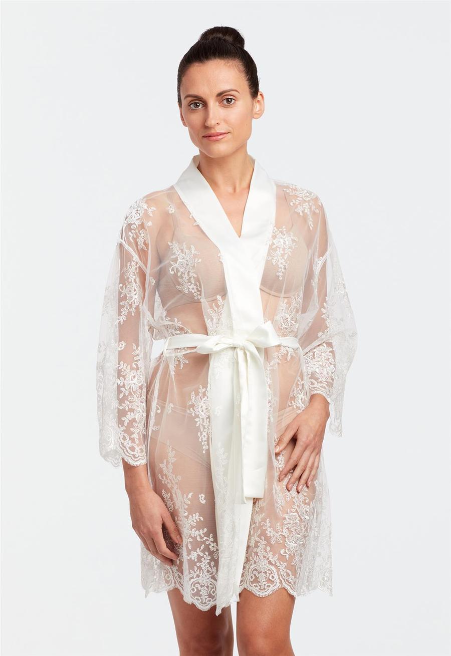 Woman wearing a white lace robe on a plain background