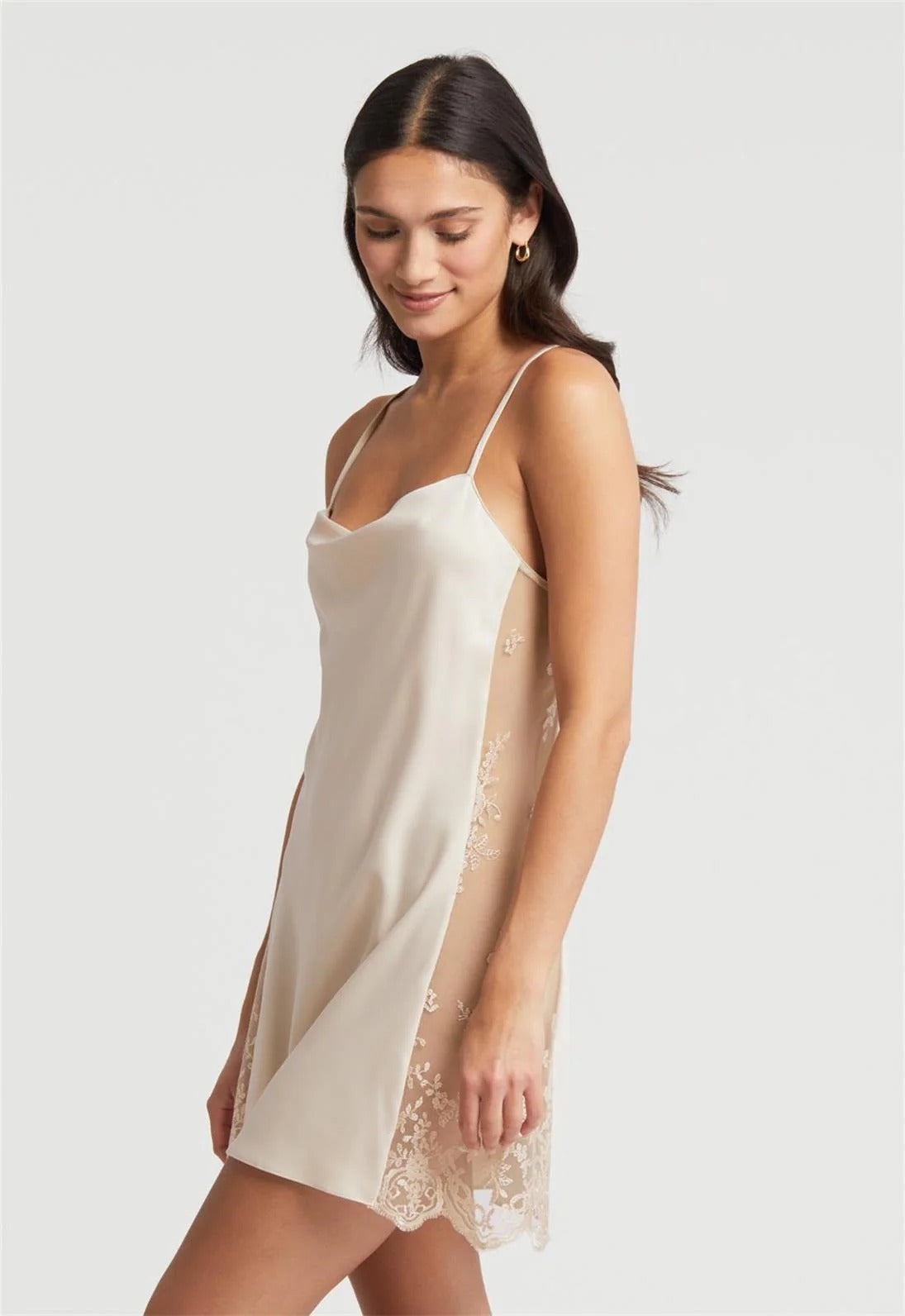Woman wearing a beige slip dress with lace details on a white background
