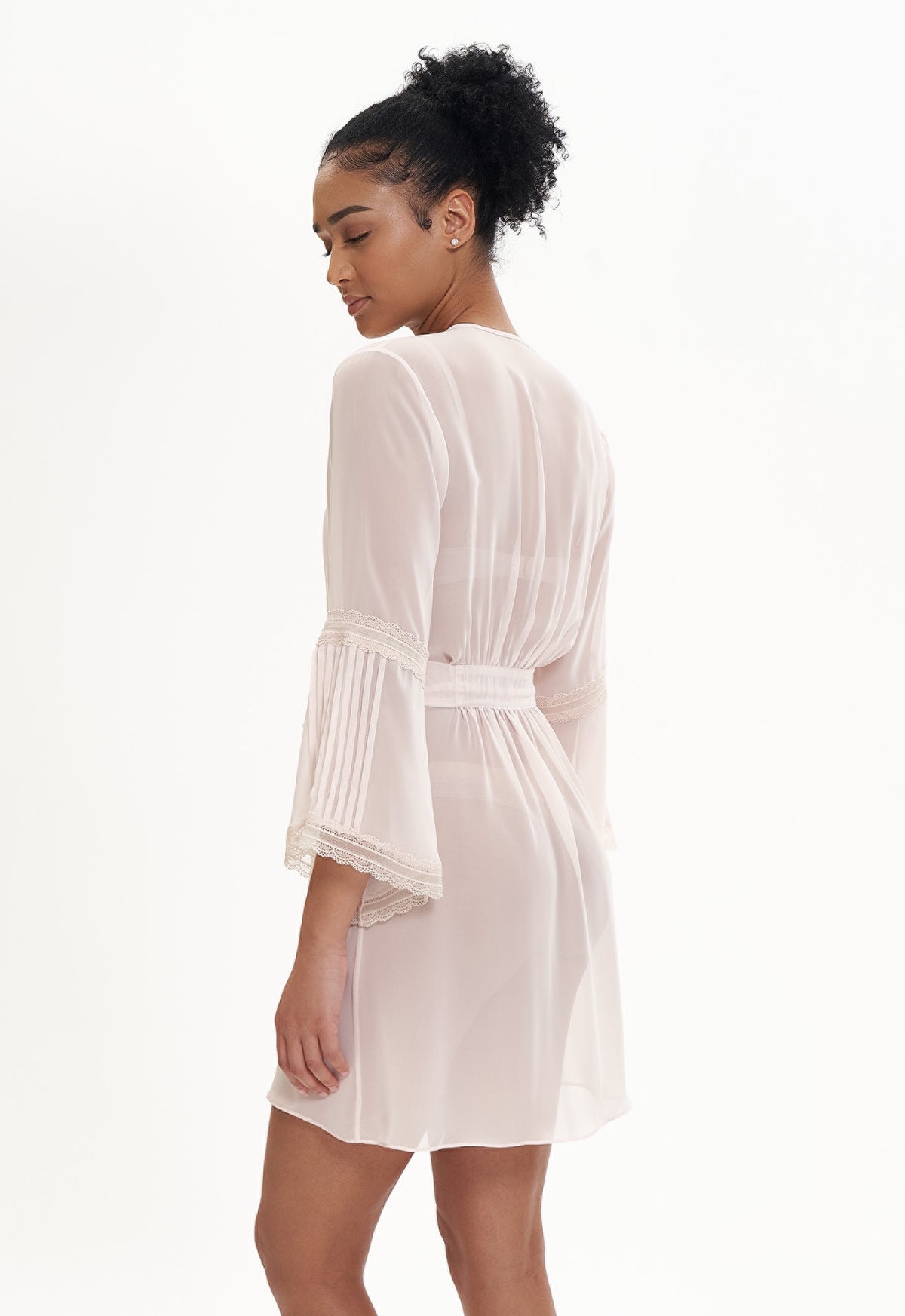 Woman wearing a soft pink sheer robe on a white background