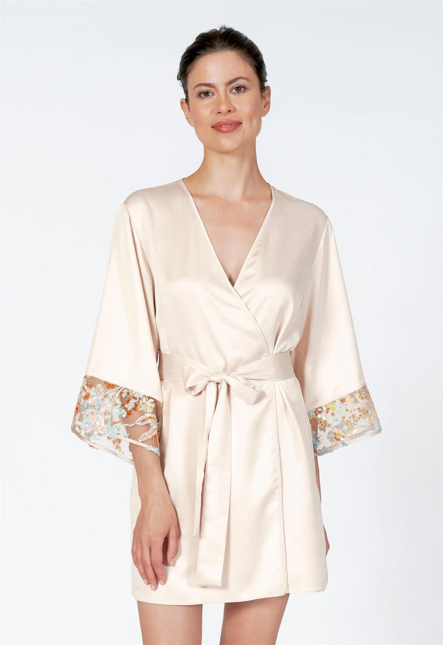 Woman wearing a beige satin robe with lace cuffs on a white background