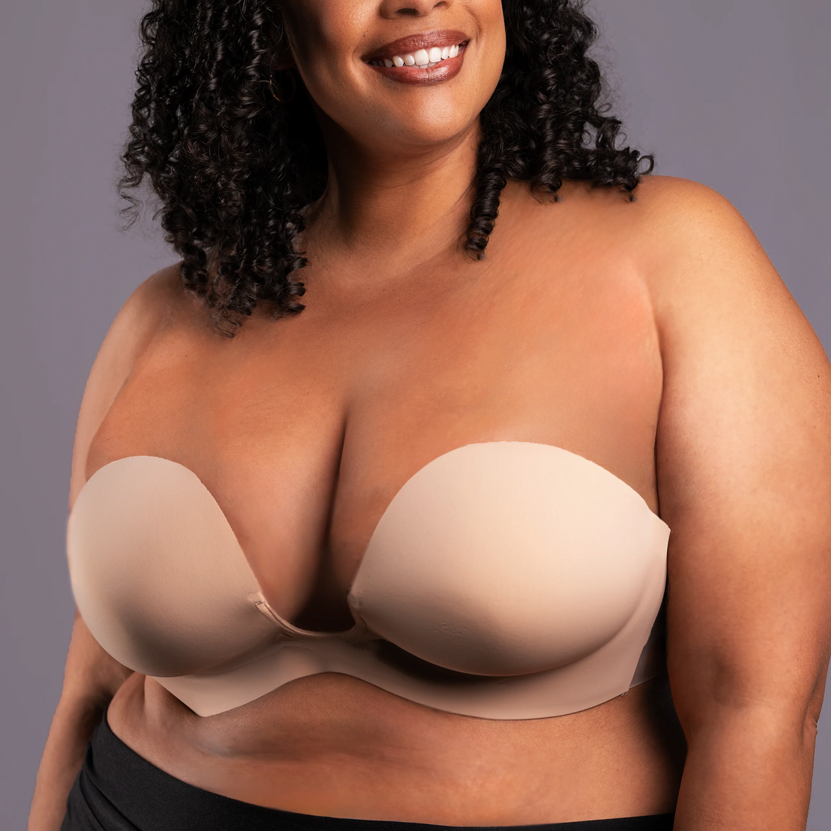Woman wearing a beige strapless bra against a gray background