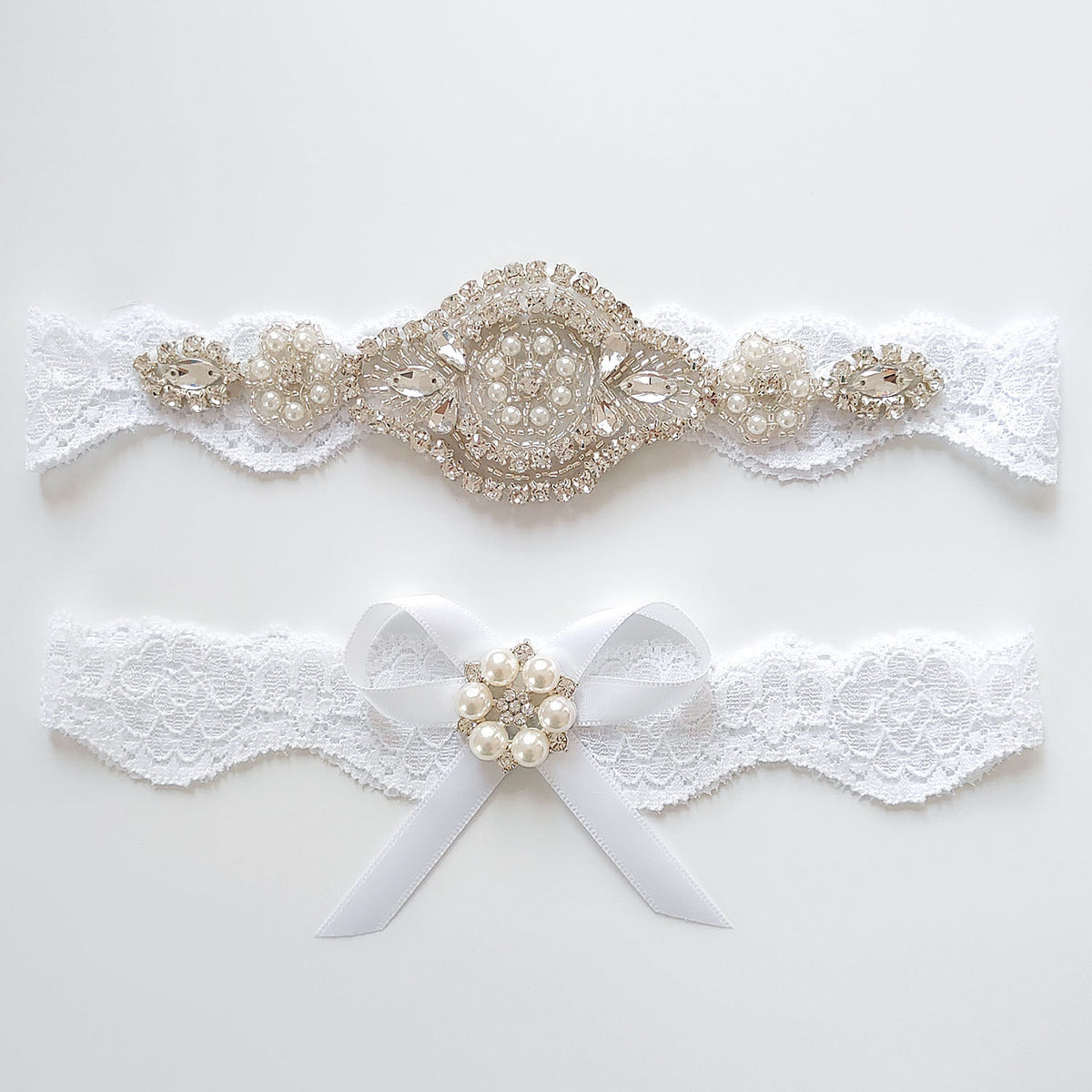 Pair of decorative garters with lace and pearl embellishments on a white background