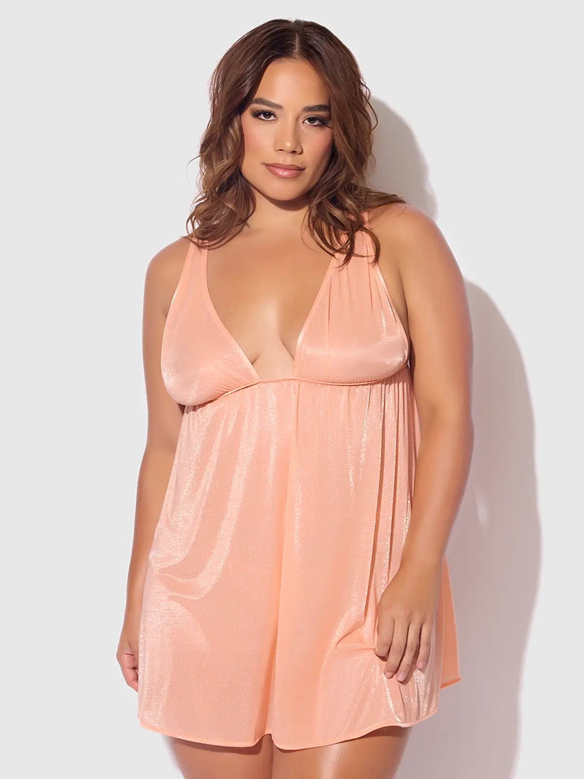 Woman wearing a peach satin nightgown against a white background