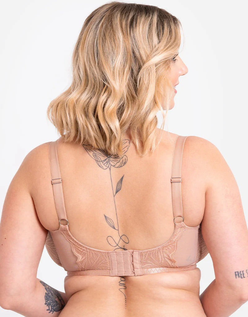 Saterra St. Jean wearing a beige bra with floral lace details on a plain background