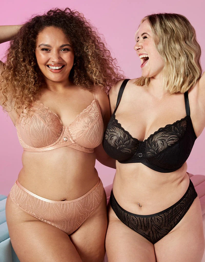 Two women wearing lingerie against a pink background