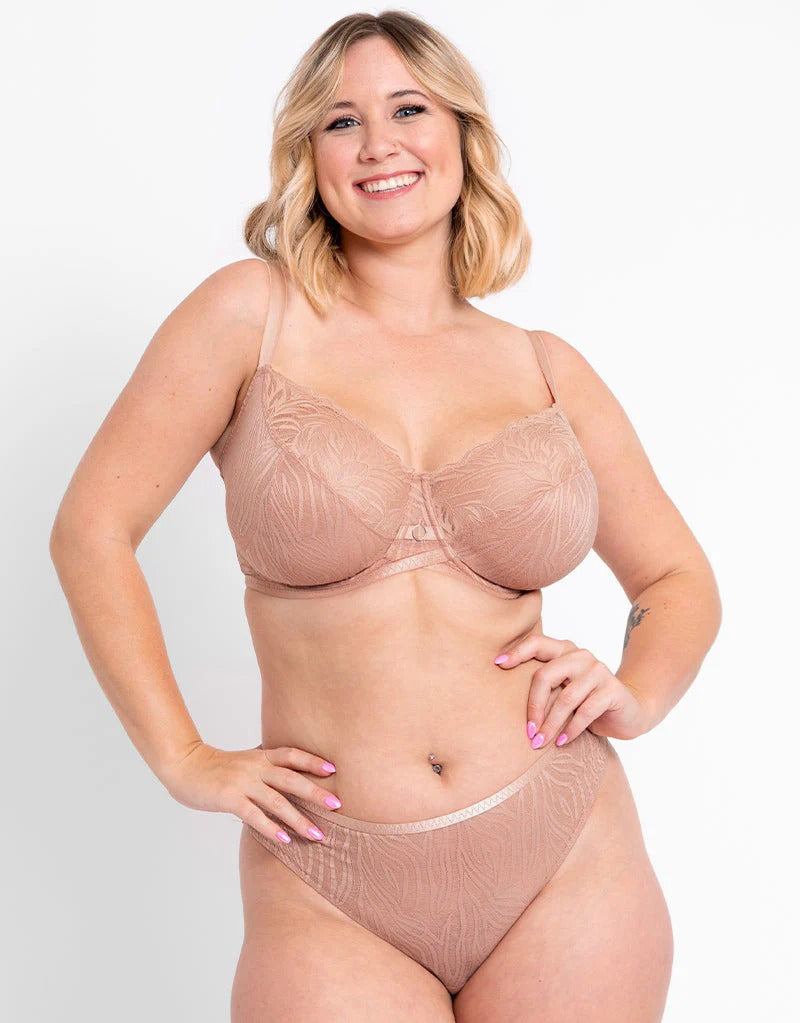 Saterra St. Jean wearing a beige bra and panties set against a plain background