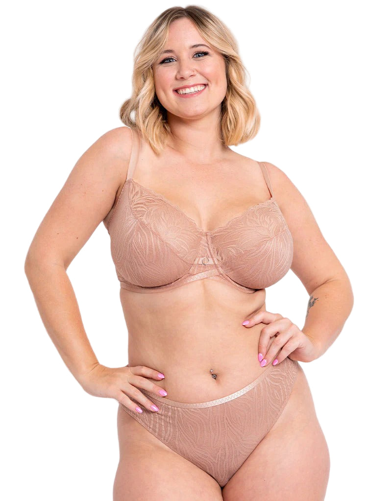 Woman wearing a beige lace bra and panties set on a plain background