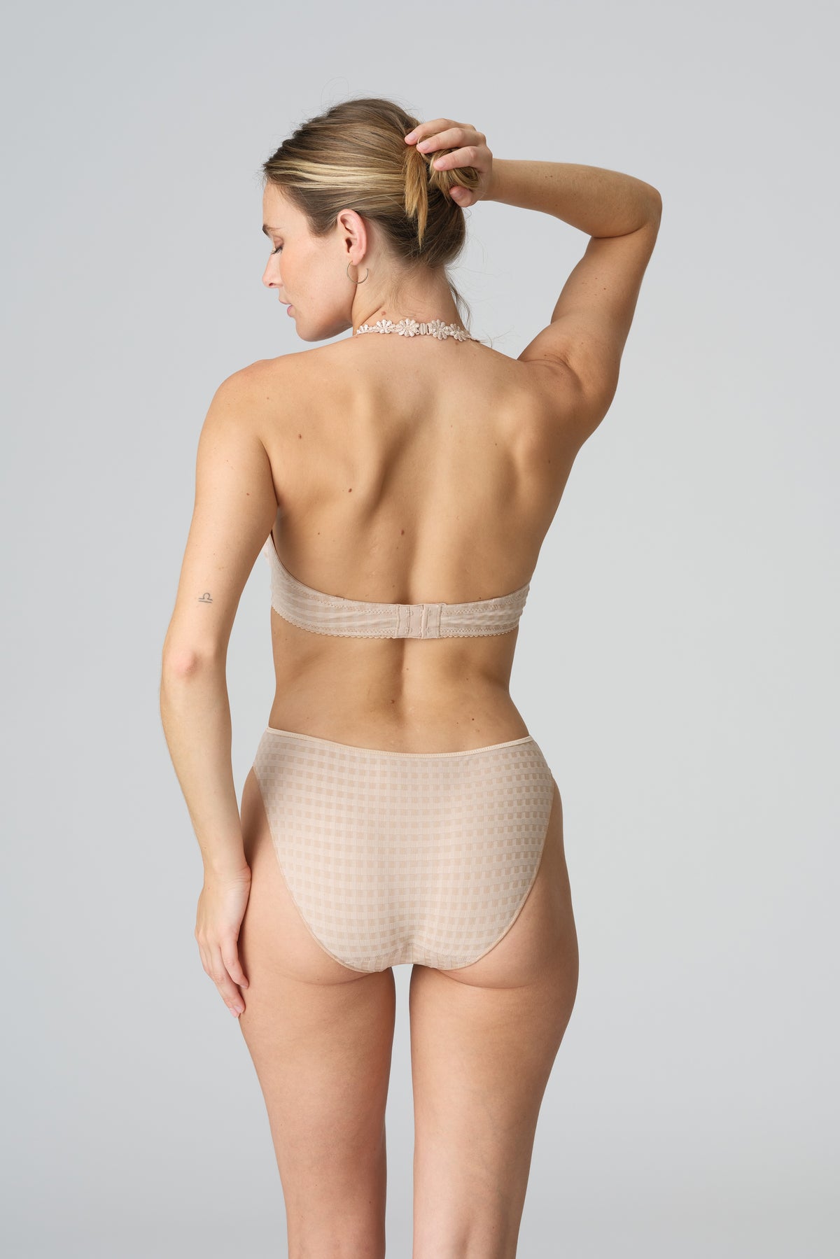 Woman wearing beige lingerie against a plain background