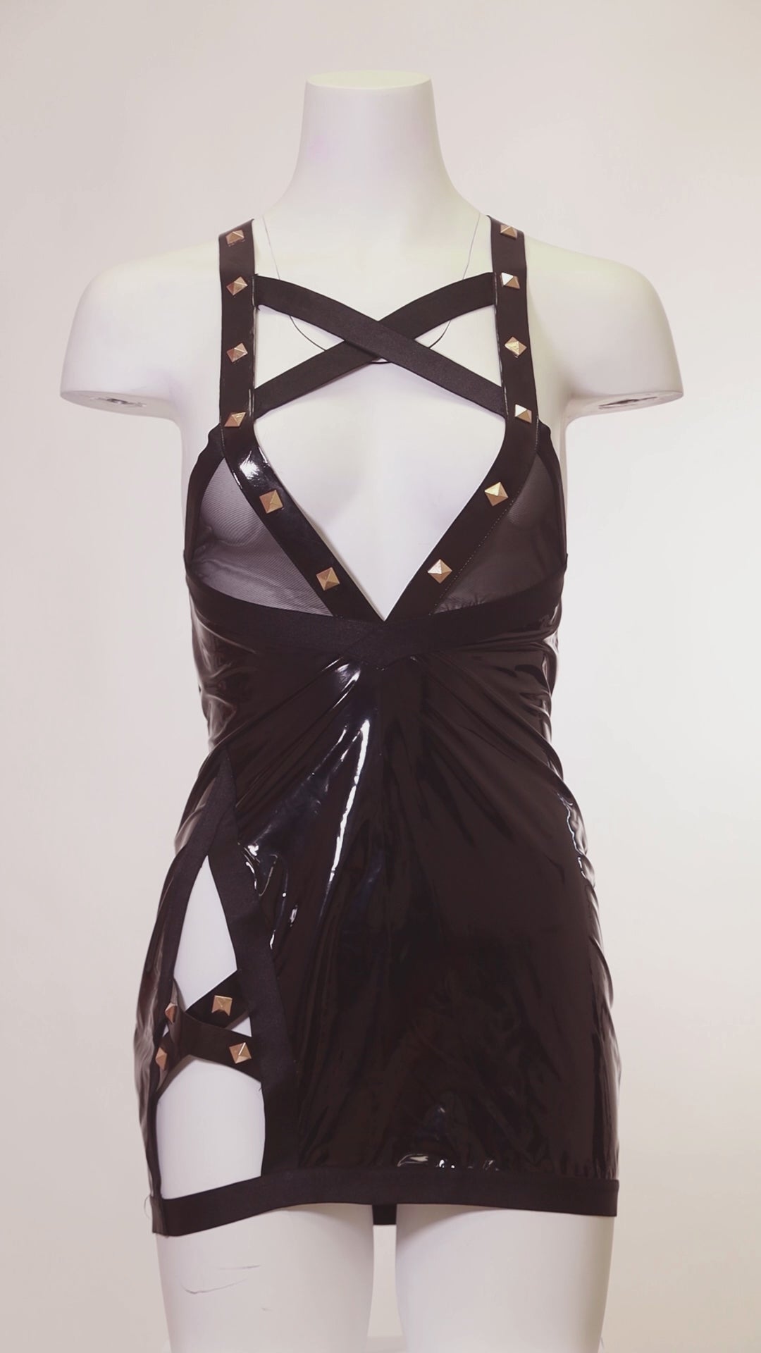 Mannequin wearing a black strappy dress with gold accents on a plain background