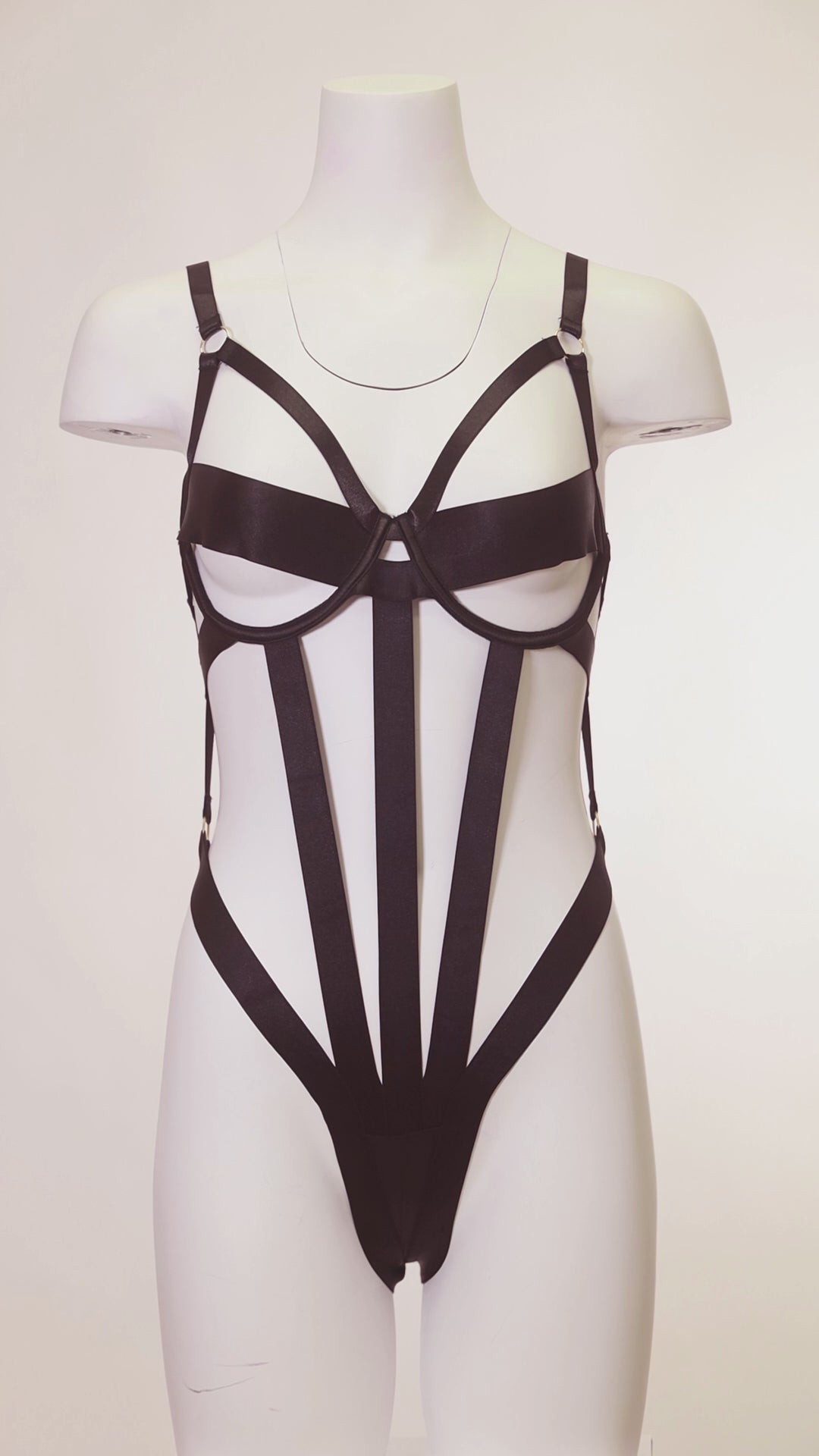 White mannequin in a black outfit with a high slit standing in a dimly lit room.