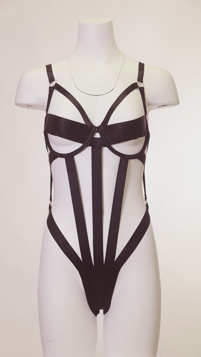 White mannequin in a black outfit with a high slit standing in a dimly lit room.