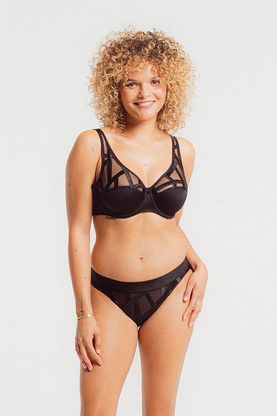 Woman wearing a black lingerie set on a plain background